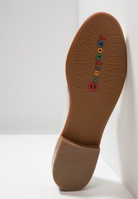 Semelle en caoutchouc brun avec motif de traction en zigzag, ornée du logo coloré "everybody" en rouge, bleu, jaune et vert. Dessus lisse et épuré.
