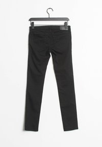 Svarta tajta jeans i ett använt stretchigt denimmaterial. Har en femfickdesign och en läderpatch vid midjan. Slät yta.