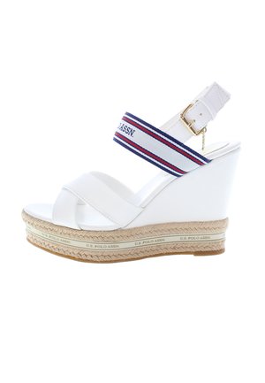 Valkoiset korokepolkuvarrelliset sandaalit, joissa on ristikkäin nauhoitus, tekstiilipohjainen nilkkaremmi, jossa on punaisia ja sinisiä raitoja, sekä punottua juteen muistuttavaa yksityiskohtaa pohjassa.