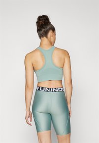 Conjunto de roupa activewear verde claro, composto por um sutiã desportivo com alças nas costas e calções de cintura alta com uma faixa preta, textura suave e design ajustado.
