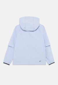 Ljusblå, hooded jacka med långa ärmar, som har en avslappnad passform och en svart Nike-logga vid kanten. Slät tyg och minimalistisk design.