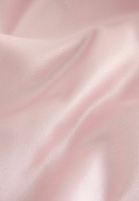 Jasnoróżowa satynowa tkanina o gładkiej, błyszczącej fakturze, z miękkimi fałdami i subtelnym połyskiem, idealna do eleganckich ubrań lub dekoracji wnętrz.