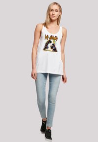 White tank top with a colorful graphic featuring an abstract triangular design and text. Paired with light blue skinny jeans and black shoes.