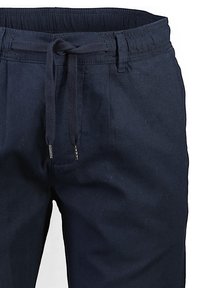 Námořnické modré kalhoty s elastickým pasem a nastavitelným šňůrkovým zapínáním. Mají přední záhyby a hladkou bavlněnou texturu.