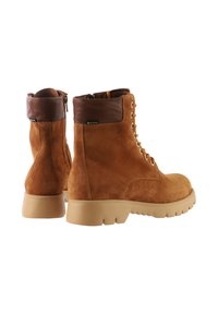 Brune ruskinds snørebåndsstøvler med en brun læderkrave, tykk beige gummisål og metaløjer, der har et vandtæt Gore-Tex mærkat.