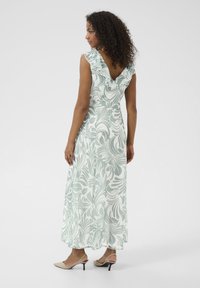 Robe maxi vert clair avec un motif floral blanc en spirale. Elle a des manches volantes et un dos en V. Ajustement slim, tombe jusqu'aux chevilles.