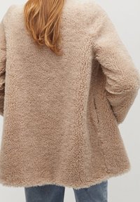 Faux fur jakke i lyse beige, med en blød overflade og en løs pasform. Har dropped shoulders og en subtil, fyldig finish.