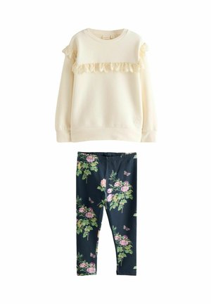 Maglione crema con bordo in pizzo e leggings blu scuro a fantasia floreale con fiori rosa e verdi. Entrambi i capi sono realizzati in tessuto morbido.