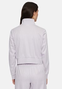 Lila cropped jack met ribbeltextuur en hoge kraag. Voorzien van een verticale streepdessin en elastische manchetten. Gstyled met bijpassende broek.