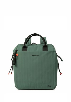 Sac à dos Hedgren vert en forme carrée avec poignées noires, fermeture éclair et cordons accentués, présenté sur fond blanc.