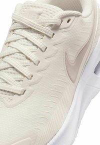 Lichtbeige sportshoe met een gestructureerde mesh bovenkant, witte rubberen zool, subtiele logo detail en platte veters met een zigzagpatroon.