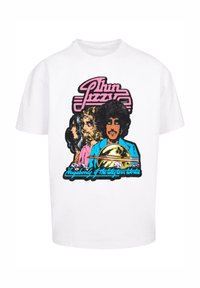 Balta medvilnine marškiniais, kuriuose yra daugiakryptis grafiškas piešinys su trimis figūromis, laikantis tromboną, tekstu "Thin Lizzy" ir "Vagabond of the Western Worlds."