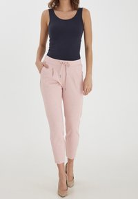 Granatowa koszulka bez rękawów zestawiona z jasnoróżowymi spodniami dresowymi z elastycznym pasem i sznurkiem. Gładka faktura z bocznymi kieszeniami.