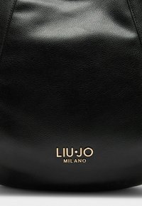 Borsa a mano in pelle nera con superficie texture. Presenta il logo dorato "LIU•JO MILANO" nella parte inferiore. Design semplice e curvo.