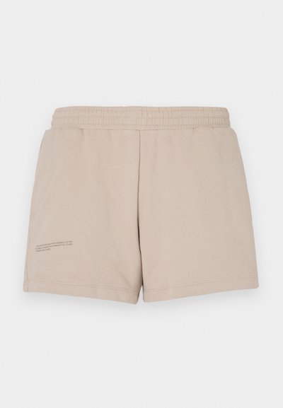 Beige Baumwollshorts mit einem elastischen Bund, der ein kleines Textdetail auf der unteren linken Seite aufweist. Glatte Textur, lässiges Design.