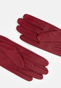 Rote Lederhandschuhe mit glatter Textur, die über perforierte Details an den Fingern und ein klassisches Design verfügen.