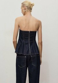 Tmavě modrý bezramenný peplum top s přiléhavým tělem, vertikálními švy a zadním zipem. Hladký zadní díl bez ozdob.