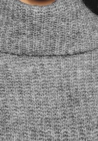 Grauer Strickpullover mit einem hohen, gerippten Kragen und einem strukturierten Muster, das ein weiches und gemütliches Design betont.