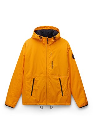 Oranssi vettä hylkivä takki hupulla, jossa on vetoketjulliset taskut, mustat metalliosat ja säädettävät kiristykset helmassa.