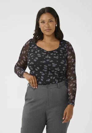 Top floral noir avec des manches longues transparentes et un décolleté en scoop, associé à un pantalon gris ajusté. Le tissu présente de petites fleurs violettes et bleues.