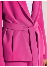 Fuchsia Blazer mit tailliertem Design, ausgestattet mit einem Gürtel in der Taille, plissierten Details und glatter Textur. Strukturierte Revers und offene Vorderseite.