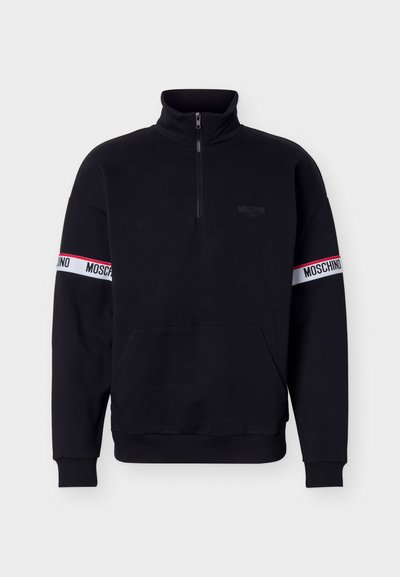 Μαύρο φούτερ με φερμουάρ μέχρι τη μέση και ψηλό γιακά, τσέπη καγκουρό και λευκές ρίγες με το κείμενο "MOSCHINO" και στα δύο μανίκια.