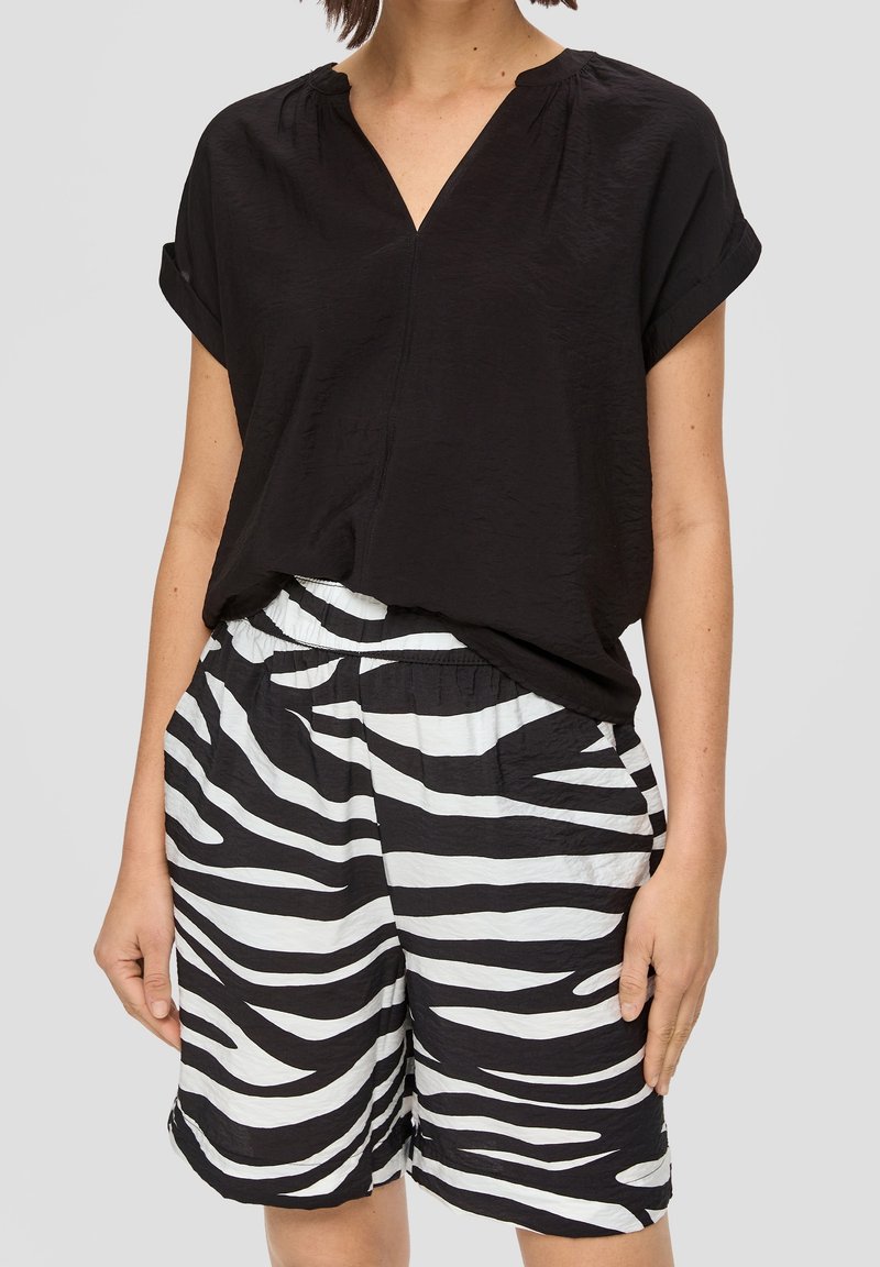 Top noir à manches courtes avec un col en V, associé à un short rayé zebra noir et blanc avec une taille élastique et des poches latérales.