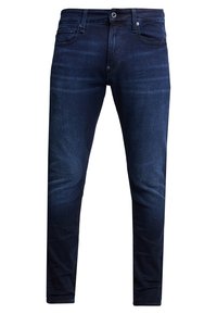 Jeans ajustados de color azul oscuro con cinco bolsillos, cierre de botón y un sutil efecto de desgaste en los muslos, mostrados de frente.