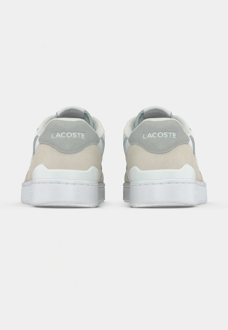 Sneakers in camoscio beige e grigio con suola di gomma bianca, caratterizzate da un logo ricamato sul retro e una texture liscia.