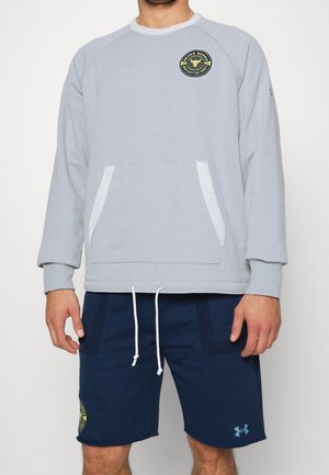 Grå bomullssweatshirt med raglanärmar, framfickor och rund halsringning; har en logotyp patch. Bärs med marinblå shorts och vita dragsnören.