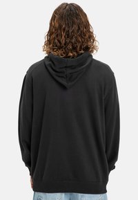 Čierna mikina s kapucňou, s pohodlným strihom, jemnou textúrou a rebrovanými manžetami. Disponuje jednoduchým dizajnom bez viditeľných log a vzorov.