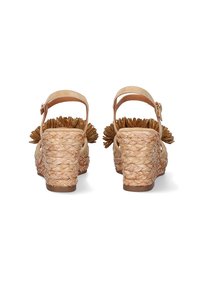 Sandalias de cuña con una base de paja tejida natural, tira ajustable de color beige en el tobillo y adornos florales decorativos en color marrón.
