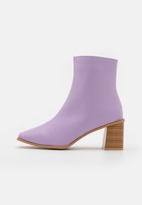 Levandulové kotníkové boty vyrobené z hladkého materiálu s špičatou špičkou a vrstveným dřevěným podpatkem, s elegantním a minimalistickým designem.