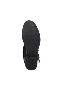 Suela de zapato negra con una superficie texturizada y surcos horizontales. Presenta un borde curvado y un ligero tacón, fabricada en material de goma duradera.