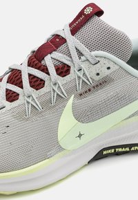 Nike trail løbesko i grå med røde accenter; har mesh-overdel, reflekterende detaljer og et lysere grønt swoosh-logo.