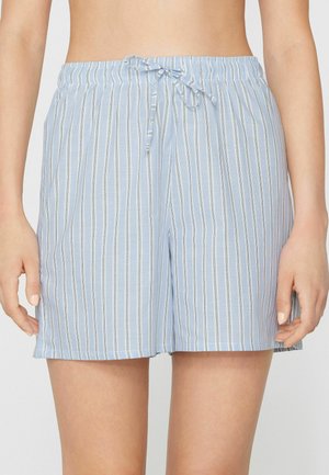 Short bleu clair avec des rayures verticales blanches et un nœud devant, porté par une personne de la taille jusqu'au milieu de la cuisse, les bras détendus sur les côtés.
