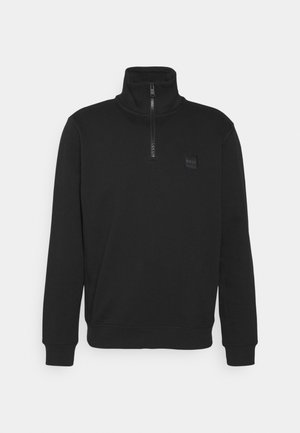 Črn pulover s visokim ovratnikom in polovičnim zadrgo spredaj. Ima strukturo v tej barvi s logotipom na prsih, rebraste manšete in rob.