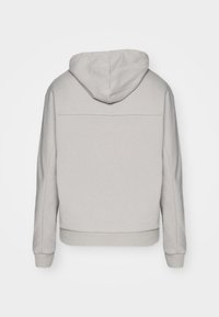 Haut de hoodie gris clair avec une texture douce, muni d'une capuche avec cordon de serrage, de manches longues et d'une couture horizontale subtile dans le dos.