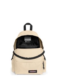 Beige canvas rugzak met zwarte accenten, een voorvak met rits, verstelbare riemen en een bovenhandvat. De binnenkant heeft een zwarte voering en een organizer.