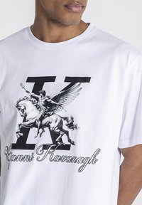 Camiseta blanca de algodón con un gran gráfico negro de una figura alada sobre un caballo, con una "K" en negrita y el nombre "Gianni Kavanagh" debajo.