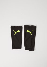 Sleeve neri per le gambe realizzati in tessuto elasticizzato, con loghi Puma giallo neon su entrambi i lati. Texture liscia con polsini elastici.