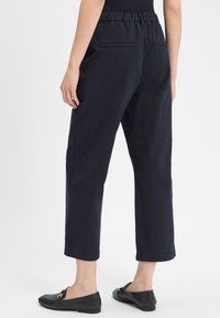 Marineblauwe cropped pants met een elastische tailleband, twee achterzakken en een rechte snit. Het materiaal lijkt glad met een lichte textuur.