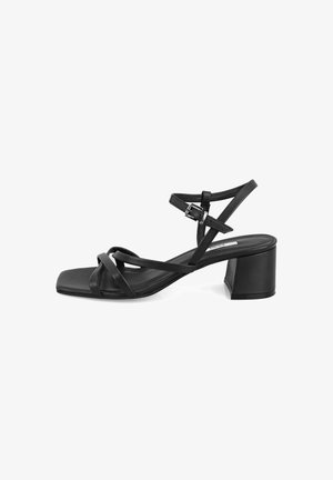 Black heeled sandal with a square toe, featuring crossed straps and an adjustable ankle buckle. Smooth leather material, sturdy block heel.
