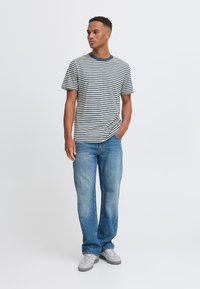 Juostuota trumpomis rankovėmis marškinėliai, melsvų ir kreminių spalvų, derinami su šviesiai mėlynomis džinsinėmis kelnėmis. Marškiniai turi apvalų iškirpimą ir laisvą siluetą.