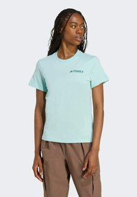 Vaaleansininen lyhythihainen Terrex-paita, jossa on pyöreä pääntie. Paidassa on pieni tumma logo vasemmassa rinnassa ja se on sileä ja pehmeä materiaali.