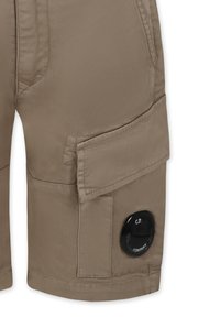 Pantaloni cargo beige con numerose tasche, caratterizzati da un accento con logo circolare nero. Realizzati in tessuto liscio, progettati per la funzionalità.