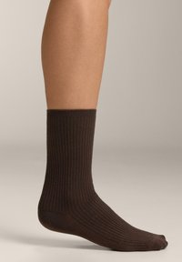 Barna bordázott zokni, közepes hosszúságú, puha anyagból készült. Megerősített orrésszel és szegéllyel rendelkezik, egységes textúrát mutatva az egész anyagon.