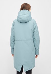 Ljusblå, huva, lång kappa med en mjuk textur och dragsko-detalj. Har en spricka bak för ökad rörlighet.