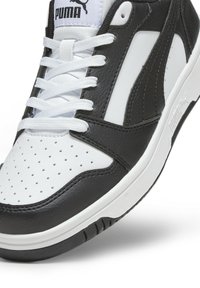 Svart och vit sneaker med en texturerad läderövre, som har perforeringar, klassiska snören och en upphöjd Puma-logotyp på tungan.