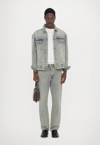 Light blue denim jacket with two chest pockets, paired with matching jeans. Plain white t-shirt underneath, black shoes, and a small brown bag.